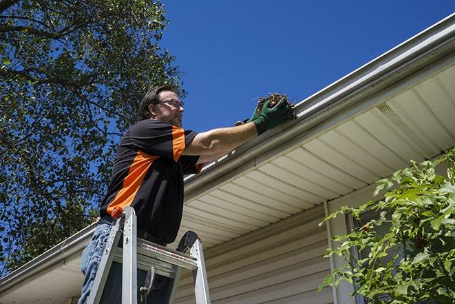 gutter repair specialist using ladder to access rooftop in Fairfield, NJ